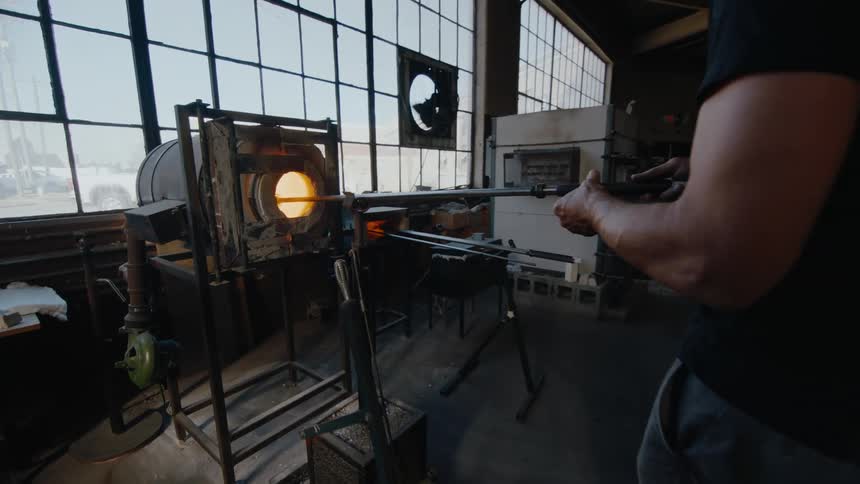 A man heats glass in a kiln