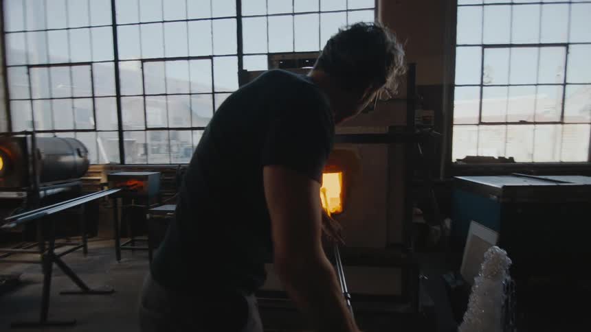 A glass blower working in his kiln in industrial studio