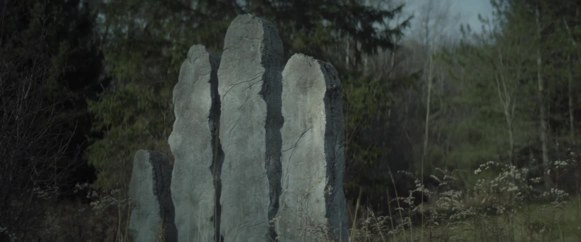 A stone sculpture is in the the woods