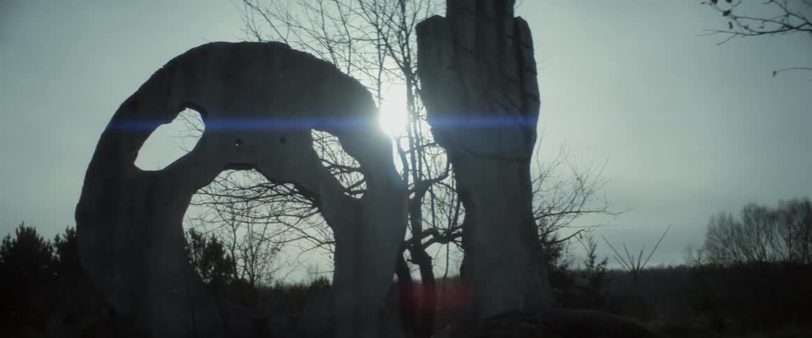 A statue of a hand and face are on the hill