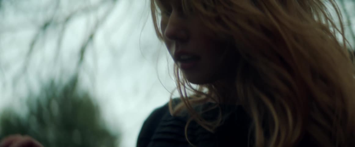 A female is standing outdoors in a forest