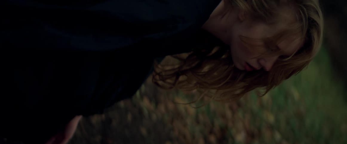 Woman is outdoors in a forest at dusk