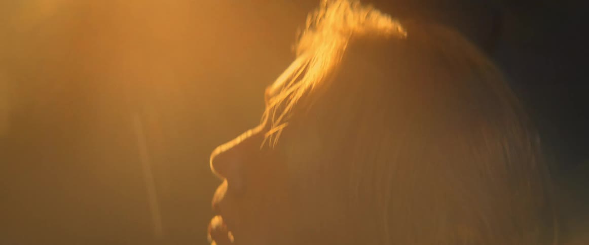 A woman is standing outdoors while the sun sets