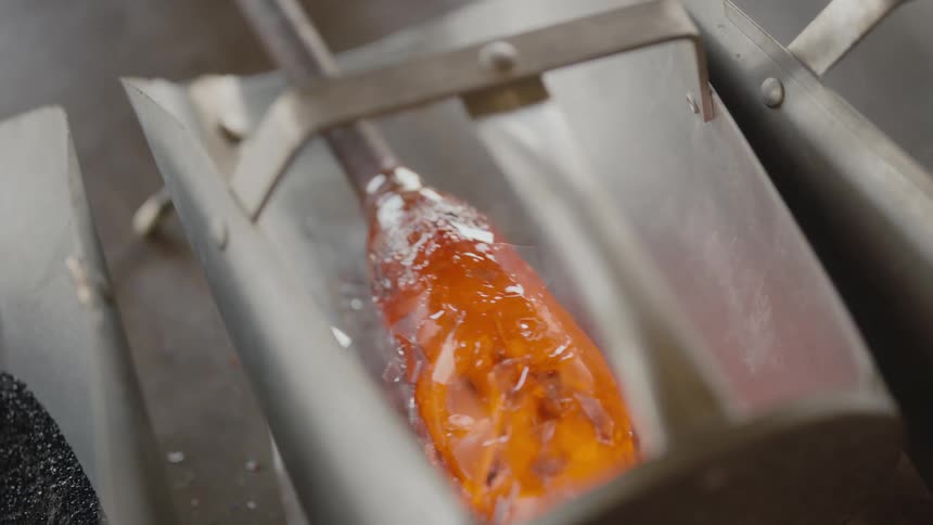 Glass maker rolls molten glass in metal container to coat exterior