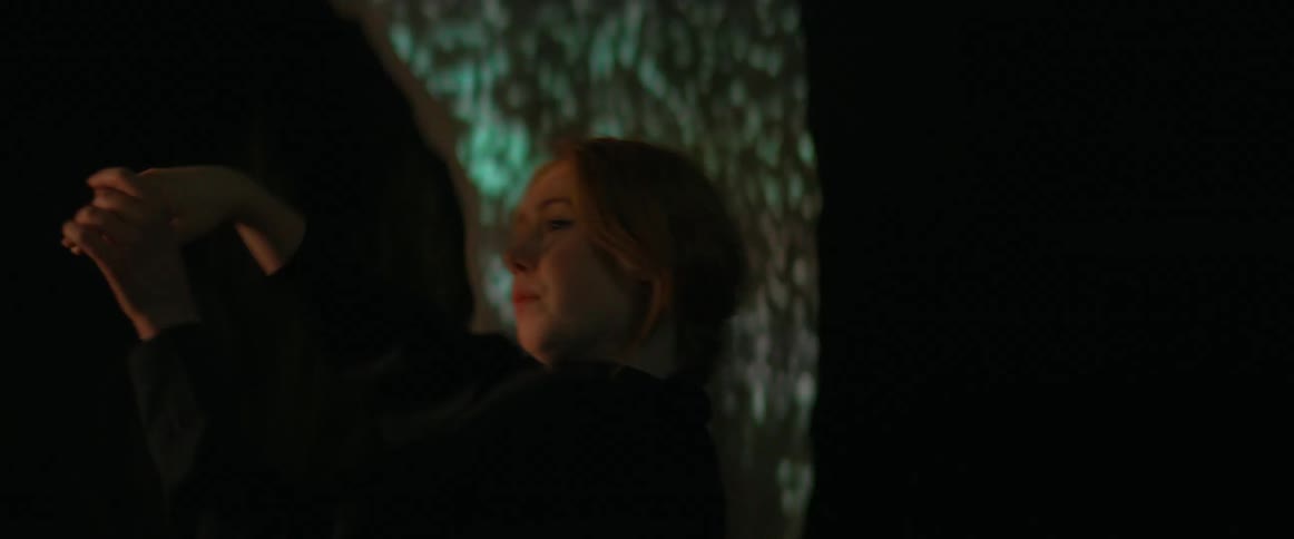 A woman is dancing in front of an electronic display at night