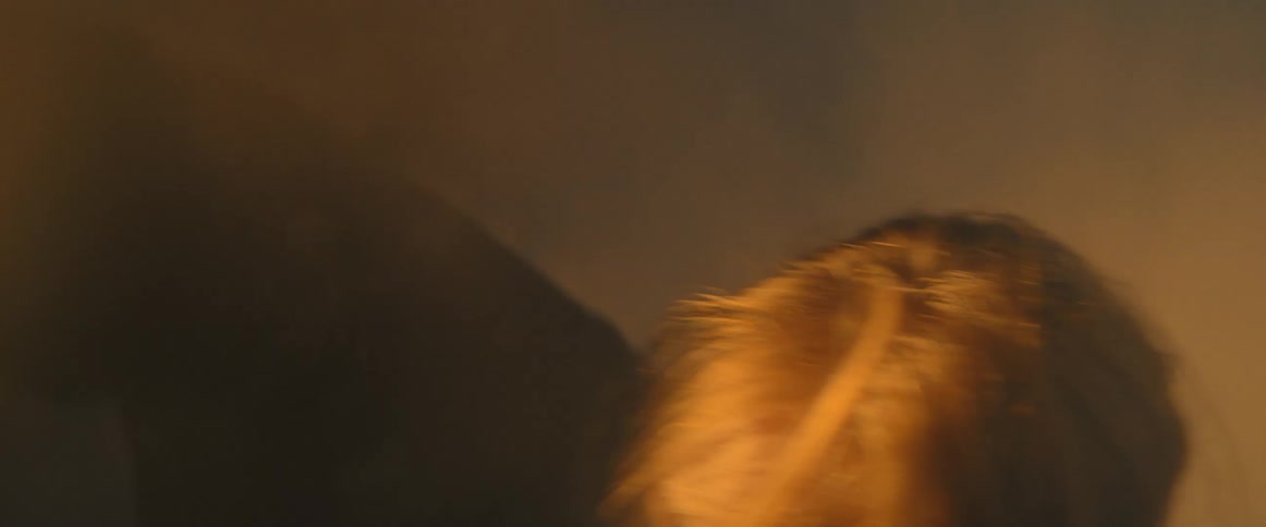 Woman dances among fog as light shines onto her intermittently
