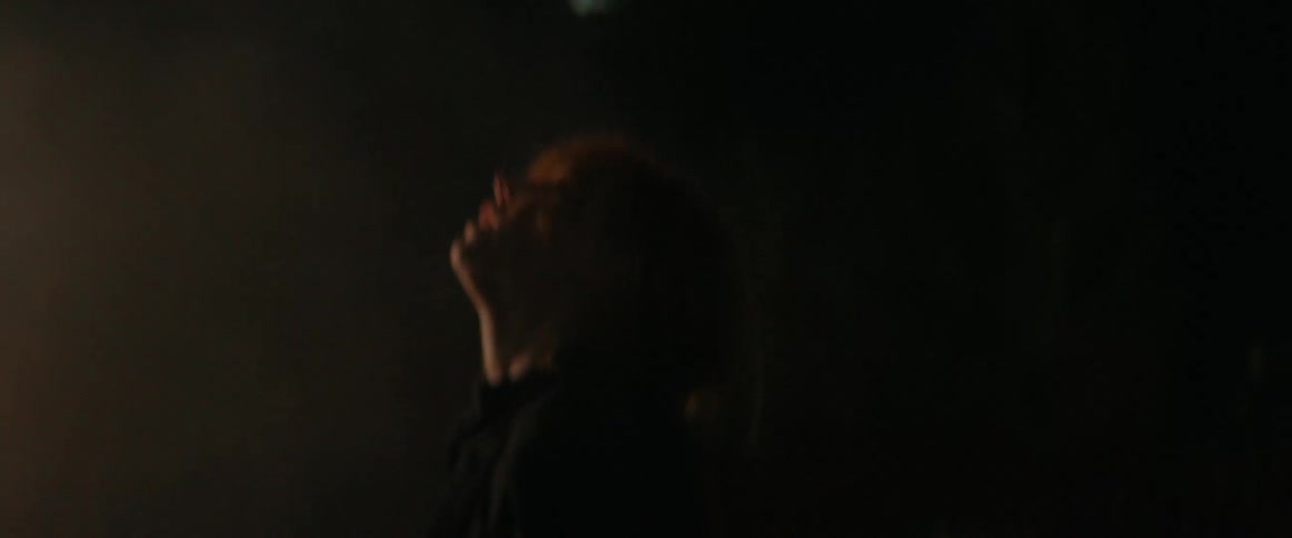 A woman is dancing outdoors near an electronic display
