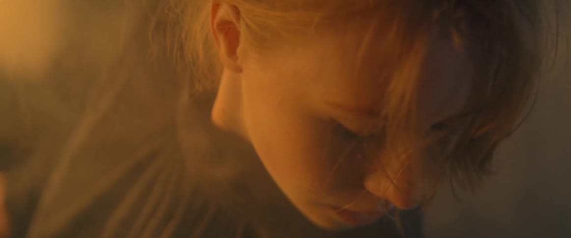 A woman is dancing outdoors with smoke and fog