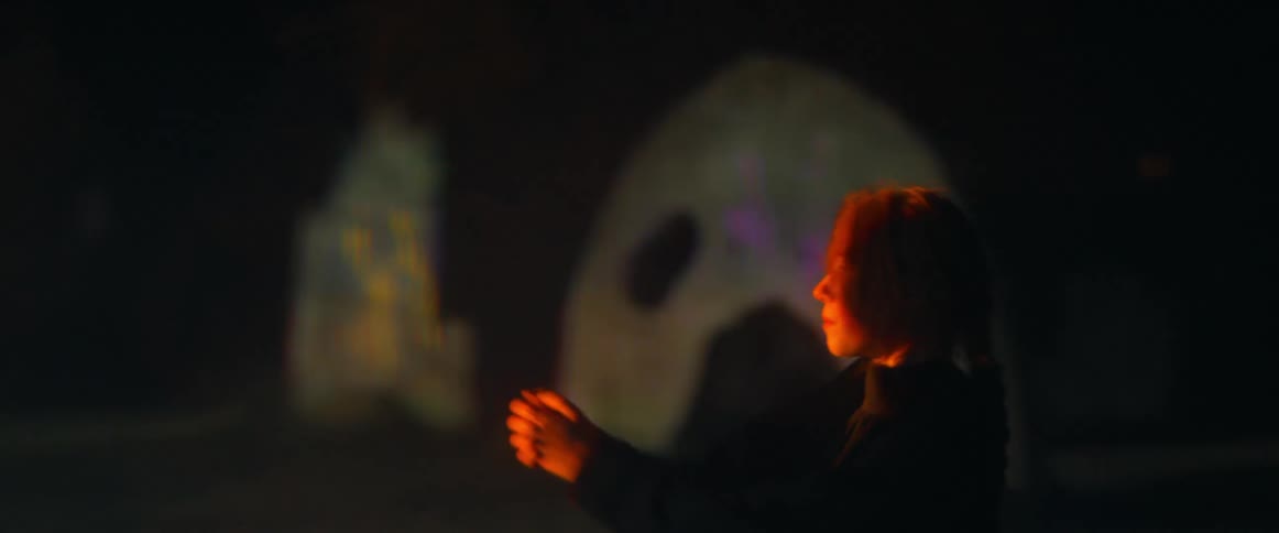 A woman moves her arm near a ray of light