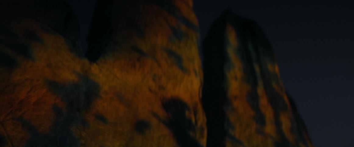 Projections over abstract concrete sculptures outdoors at night