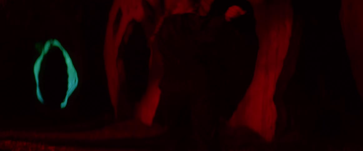 A woman dances with emotion on a dark cave set with light projected on the wall