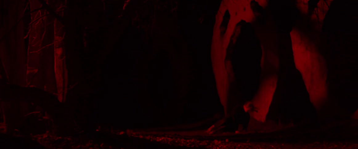 Blonde woman wearing black clothes dances in front of an outdoors sculpture at night