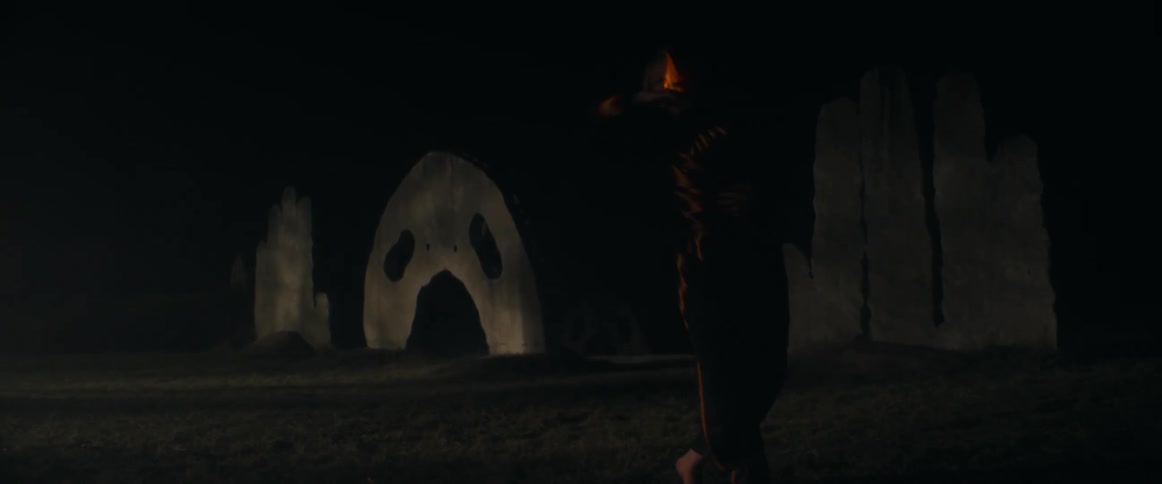Blonde woman wearing black clothes dance in front of an outdoors projection at night