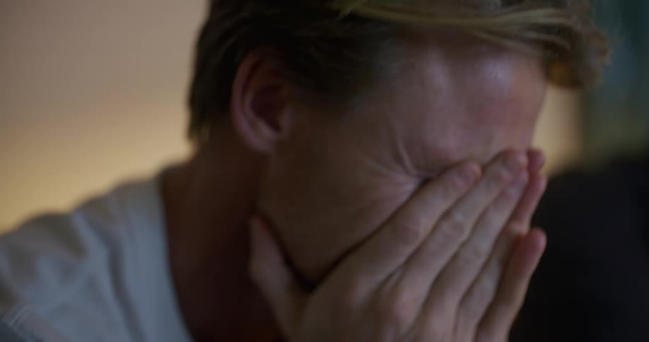 Middle aged man with white shirt watching televison gets emotional and cries