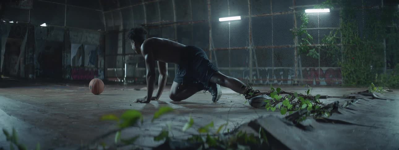 A man is crouched with a vine around his leg