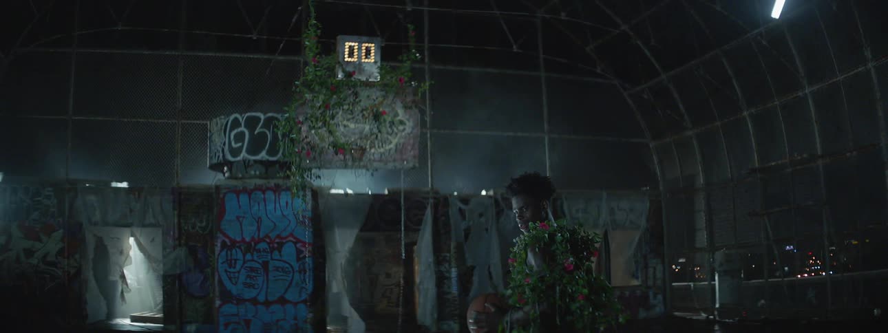 A man holding a basketball is covered with vines