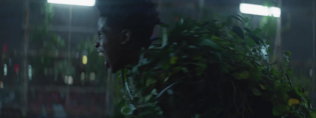 A man is yelling as he is covered with vines moving around at night