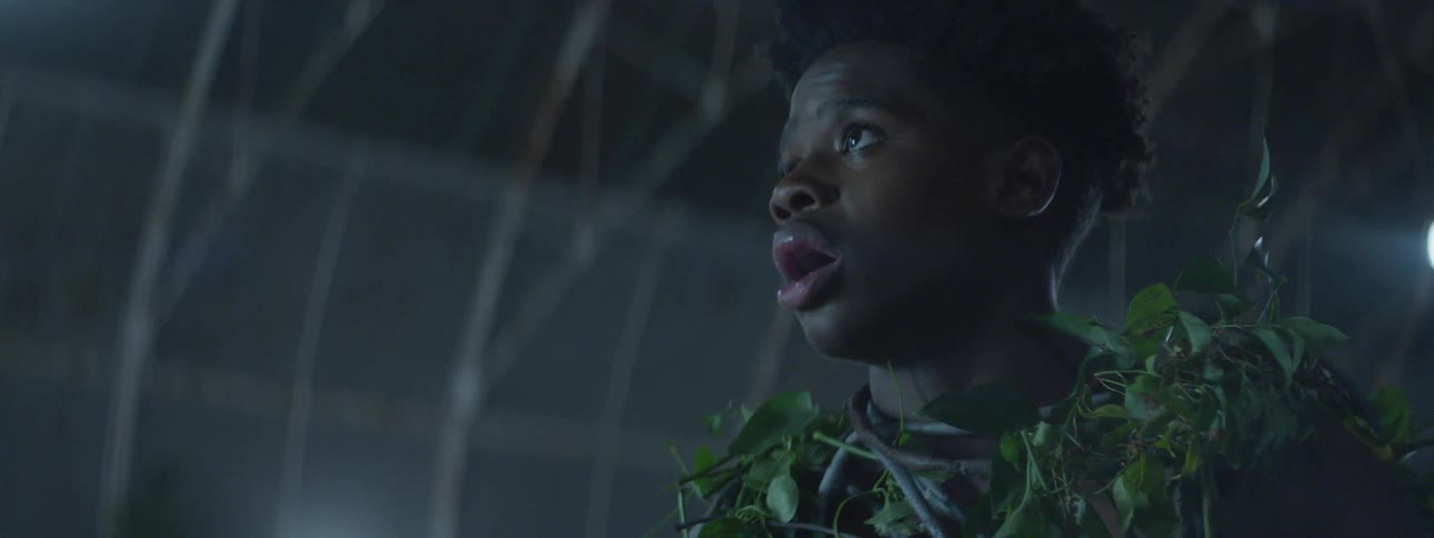 A man's mouth is open as he looks at the vines covering him