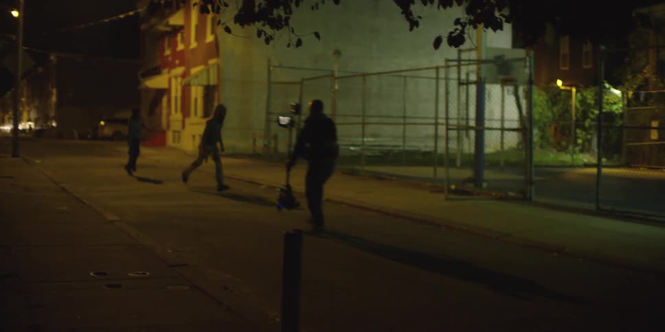 Two teenagers running with a gun while man is following with a video camera at night