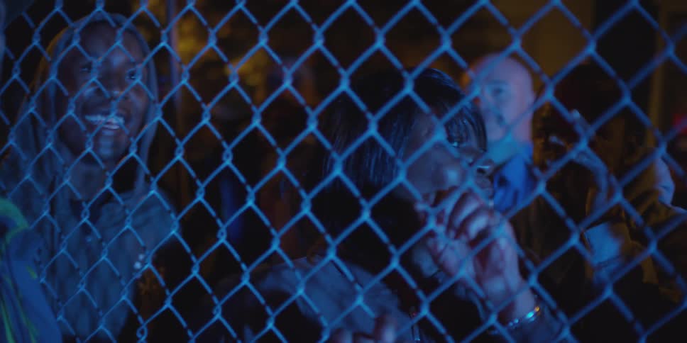People are standing by a fence at night