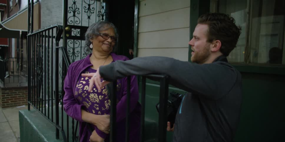 A man and women talk on the stoop of a home