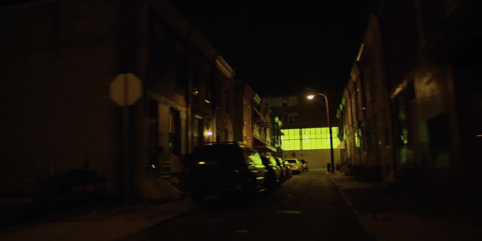 Cars are shown parked along a city street at night