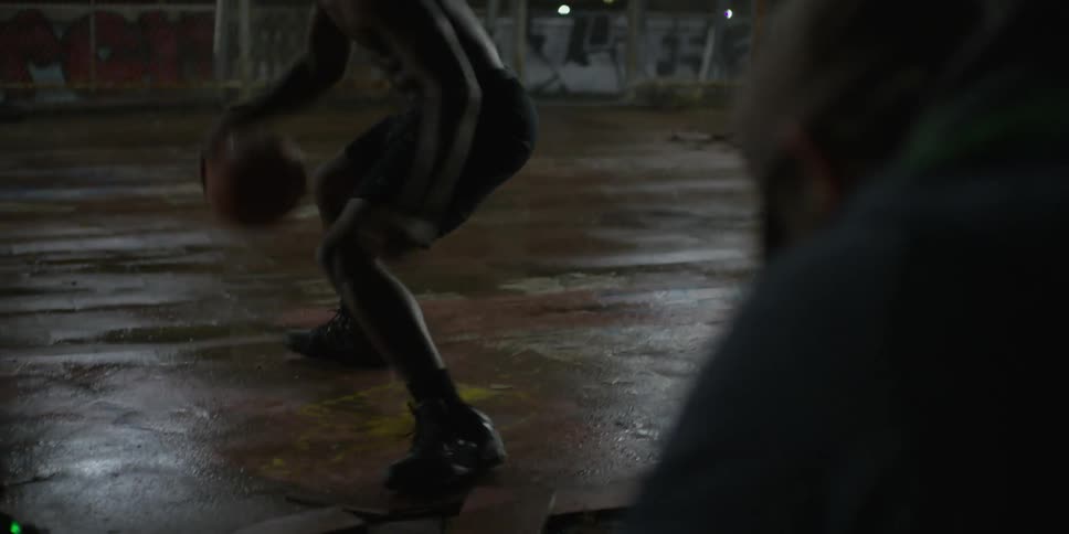 A man is dribbling a basketball at night