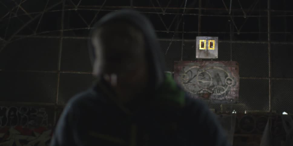 A man is standing in a court with a shot clock behind him
