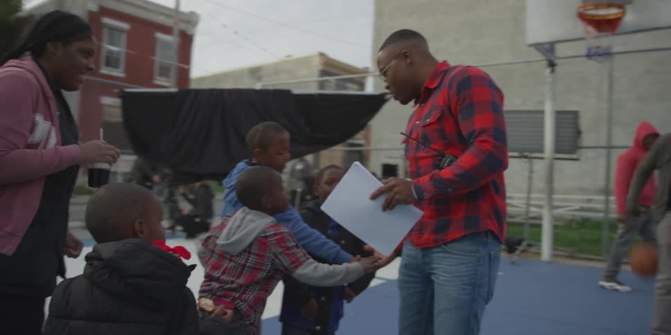 A man is talking to some kids on a basketball court