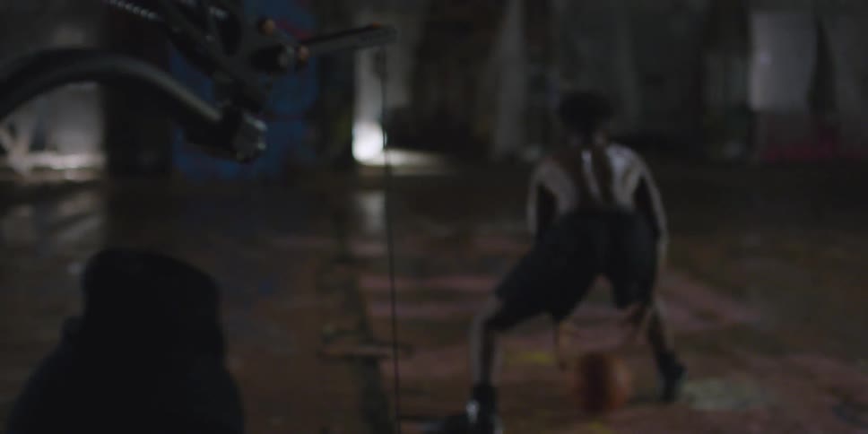 A man is filming someone dribbling a basketball at night