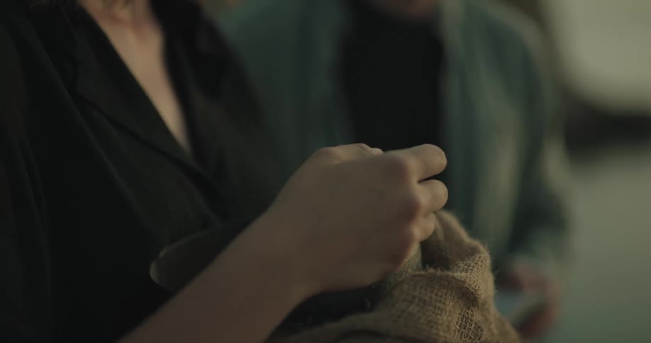 Two people spread ashes from urn wrapped with cloth