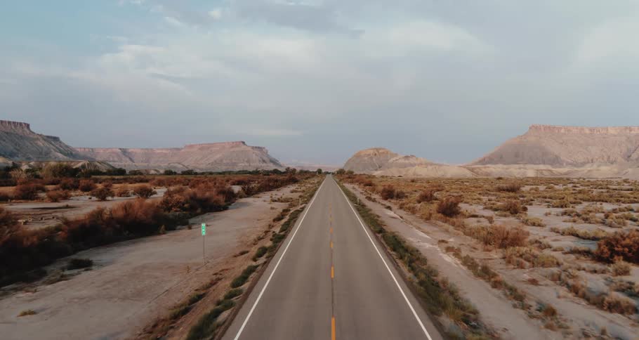 Traveling on a road through the desert badlands with mountains and mesa on the roadsides