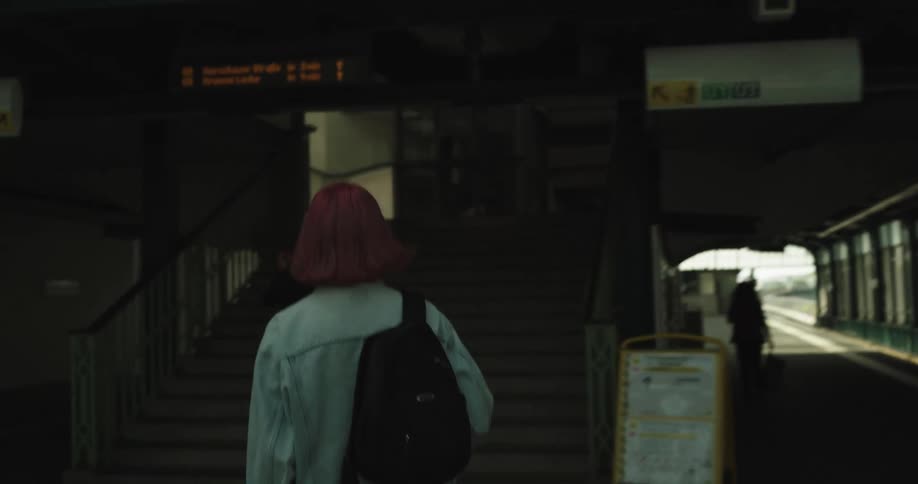 Woman walks through building with open corridor and heads up stairs