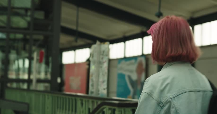 A young woman walks through a train station while carrying a backpack