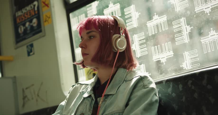 A woman is listening to headphones while riding a train