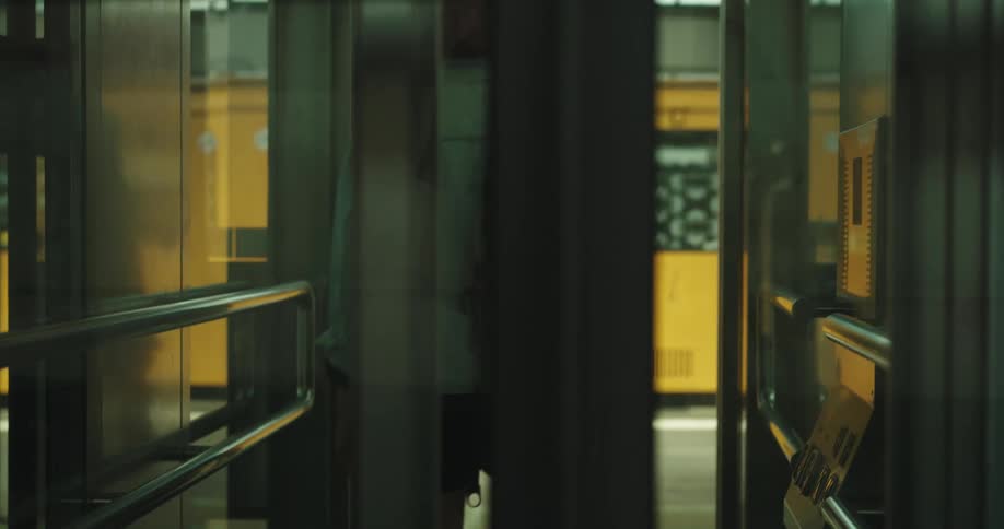 A woman exits an elevator in a train station and runs to catch the train