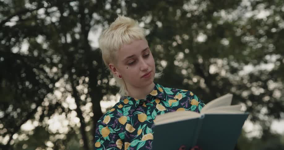 A woman is outside looking at a book