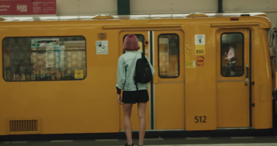A woman climbs the stairs and gets on the train