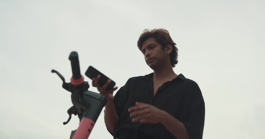 Man uses smartphone as he accesses personal scooter