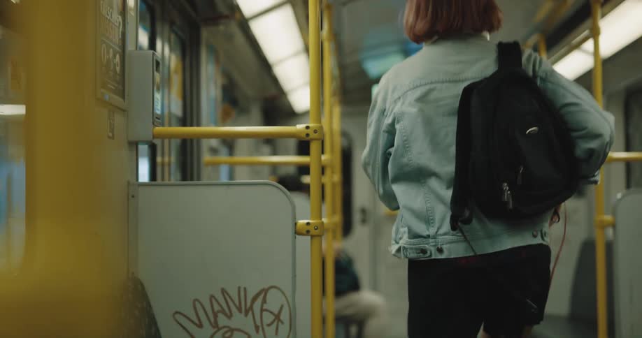 Woman sitting in train car puts book away and exits into terminal