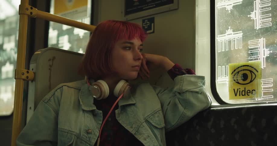 Woman with dyed hair sits in train car in a seat near the doors