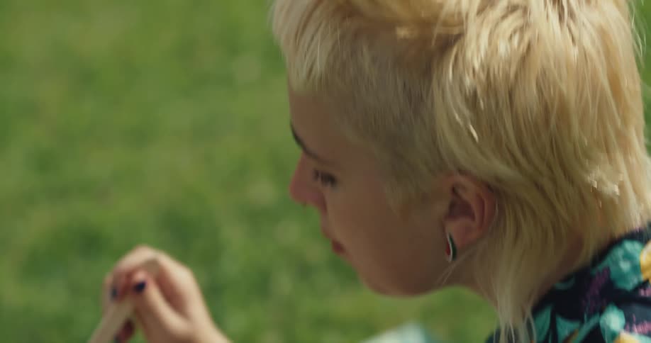 A woman is eating a meal outdoors in the grass