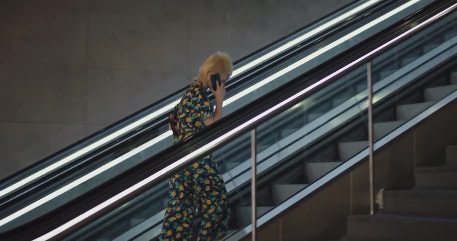 A man is walking up an escalator in a building