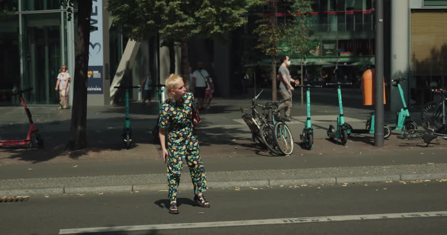 A woman waits for traffic to clear on a busy city street before running across