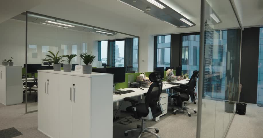 A large work area separated by glass dividers in an office building during the day