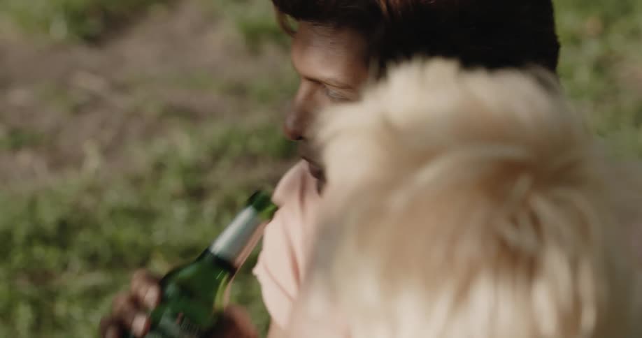 A man is drinking a beer outdoors with his friends