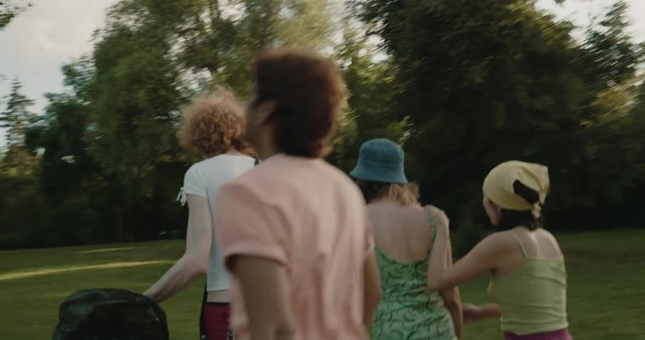 A group of people talk with one another while walking together through a park during the day
