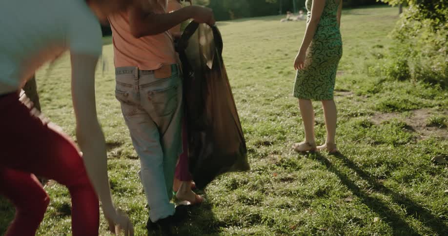 A group of young adults pick up trash in a park setting