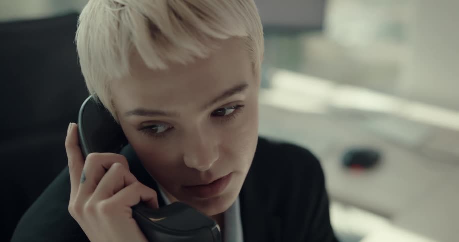 An employee is talking on a phone at her desk