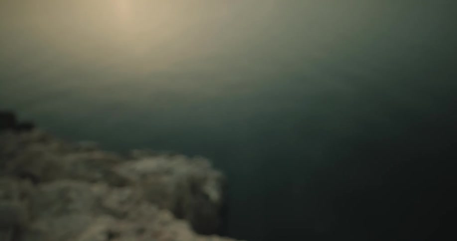 A person throwing ashes of a loved one into the ocean at sunset